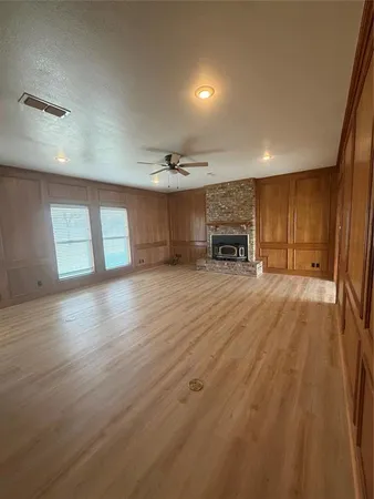 an empty room with wooden floor fireplace and windows