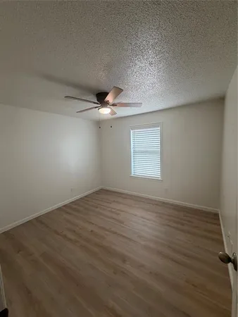 an empty room with wooden floor fan and windows