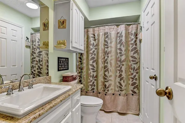 a bathroom with a granite countertop sink a toilet and a shower curtain