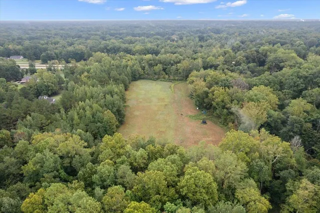 an aerial view of residential house with outdoor space and trees all around