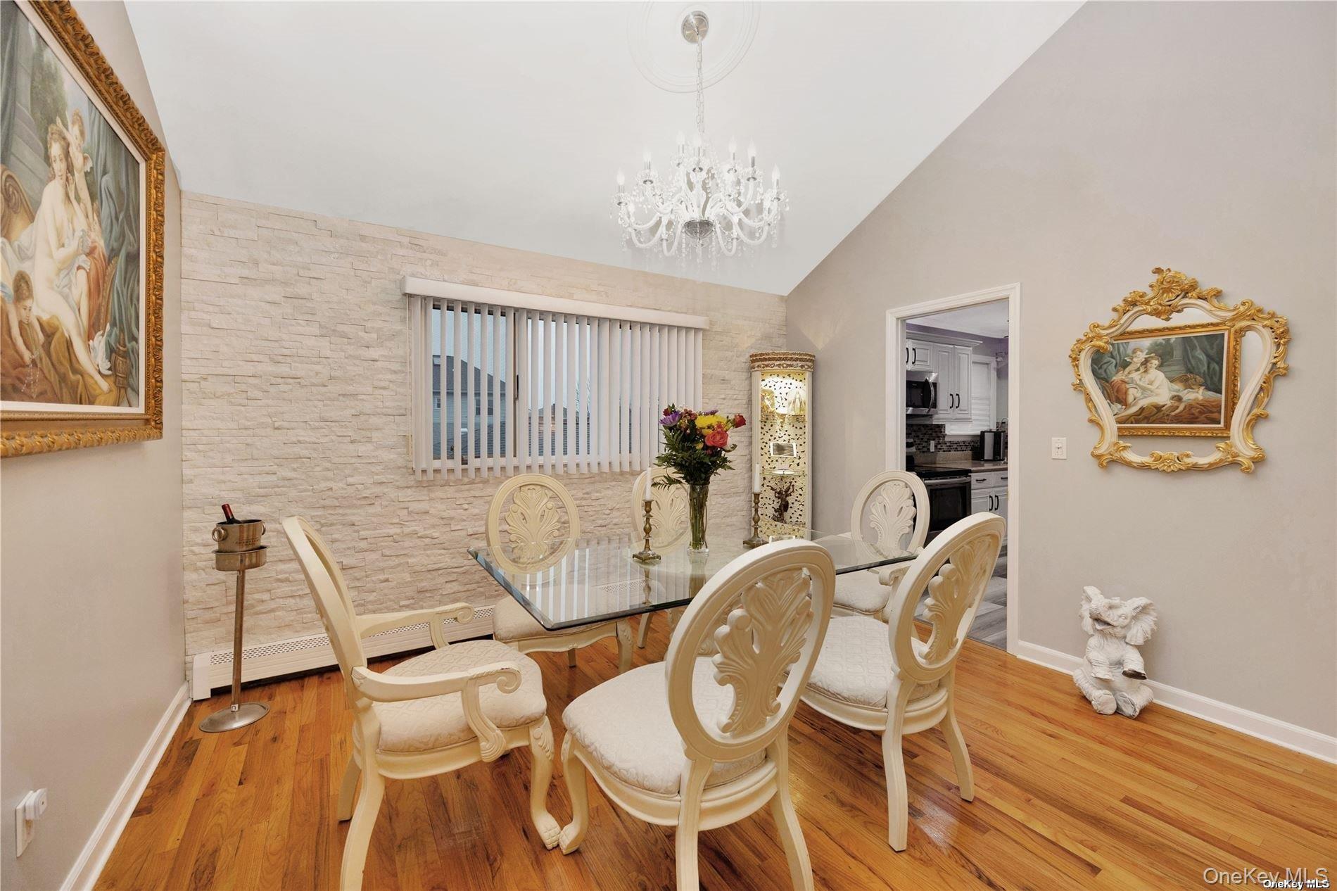245 West Chester Street Long Beach, NY 11561 - Photo 11 of 31 Dining room featuring lofted ceiling, wood finished floors, a chandelier, and a baseboard heating unit