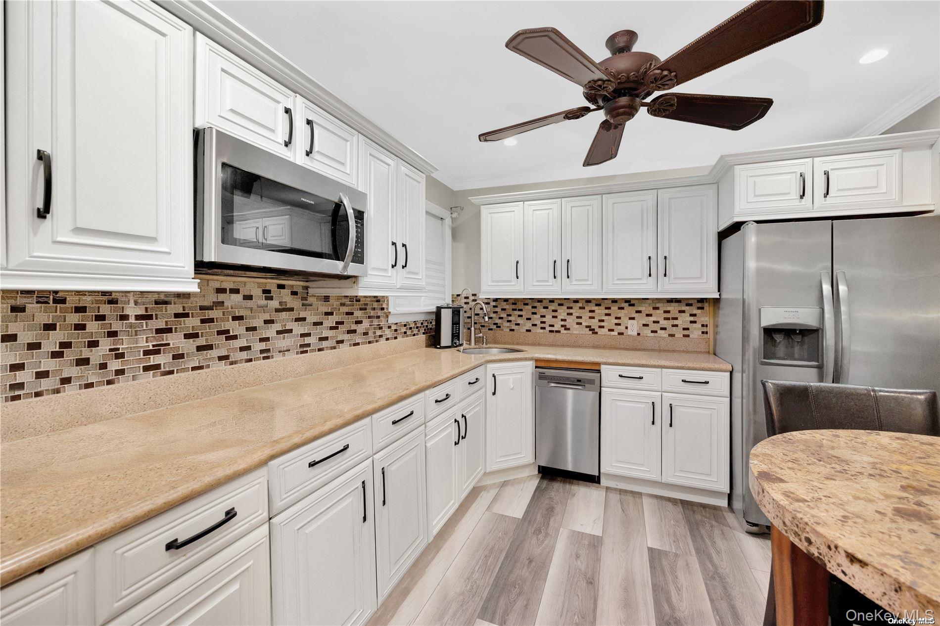 245 West Chester Street Long Beach, NY 11561 - Photo 13 of 31 Kitchen with white cabinets, stainless steel appliances, light wood-type flooring, a ceiling fan, and ornamental molding