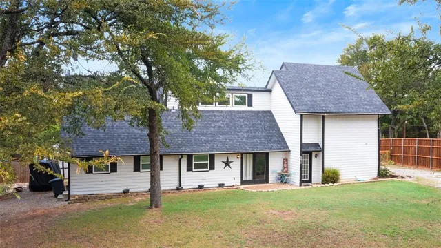 a view of a house with a yard and large tree