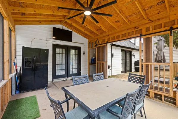 a patio with a table and chairs and potted plants