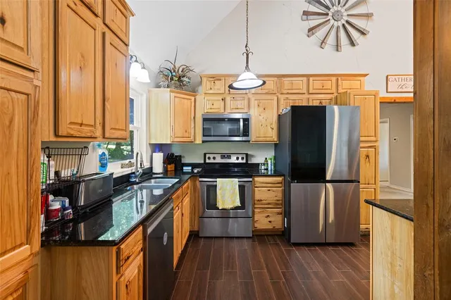a kitchen with stainless steel appliances granite countertop a refrigerator a stove and a wooden floors