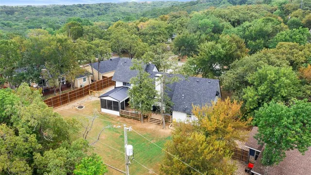 an aerial view of residential houses with outdoor space and trees all around