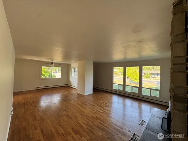 a view of empty room with wooden floor and fireplace