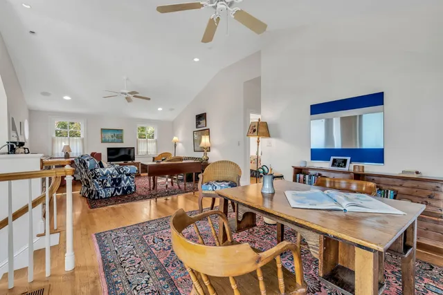a living room with furniture and a dining table with wooden floor