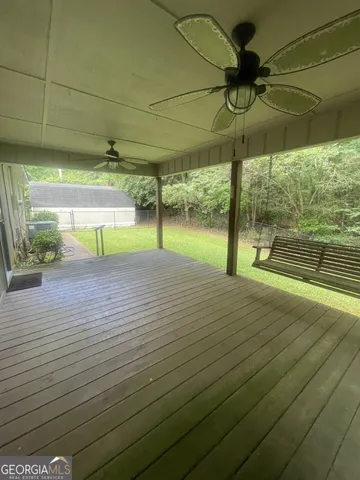 an empty room with wooden floor and fan