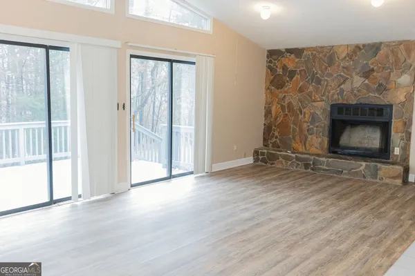 an empty room with wooden floor fireplace and windows
