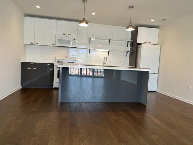 a large kitchen with stainless steel appliances granite countertop a stove a refrigerator a sink a microwave and wooden floor