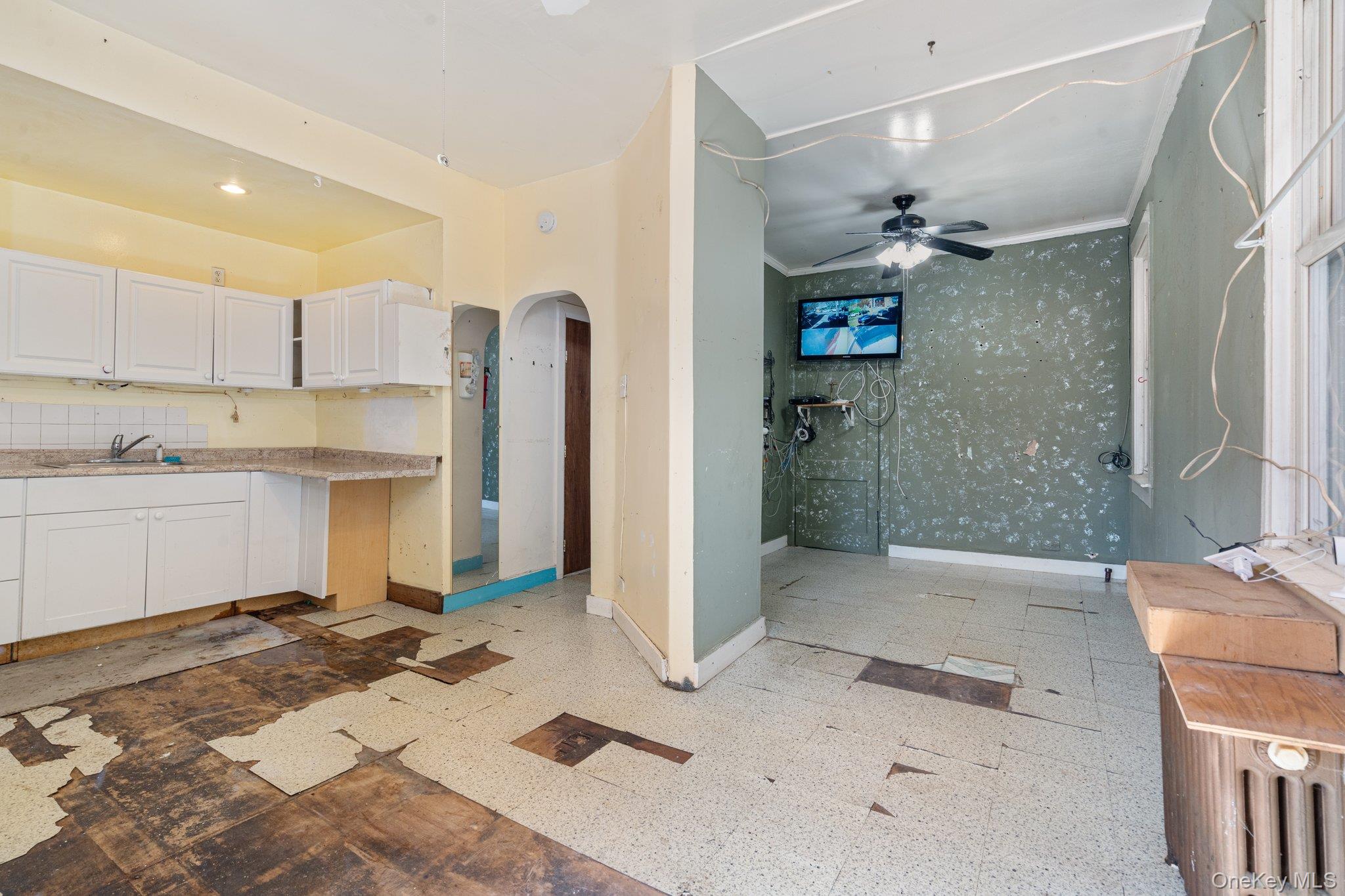 100-30 Martense Avenue Queens, NY 11368 - Photo 24 of 36 Kitchen with ceiling fan, crown molding, arched walkways, baseboards, and white cabinetry