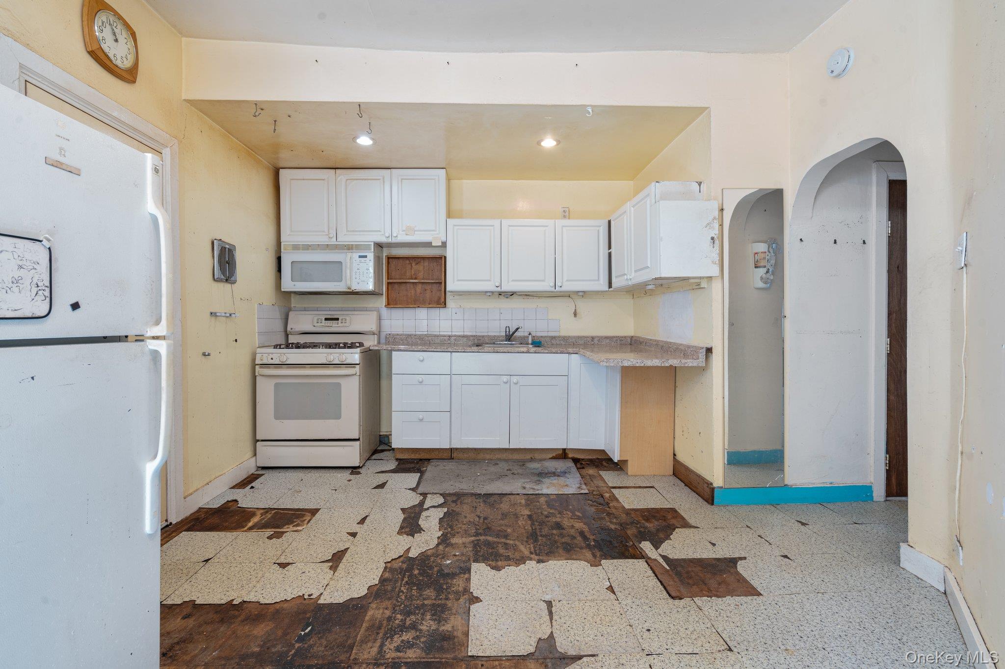100-30 Martense Avenue Queens, NY 11368 - Photo 25 of 36 Kitchen with white cabinets, a sink, white appliances, light countertops, and baseboards
