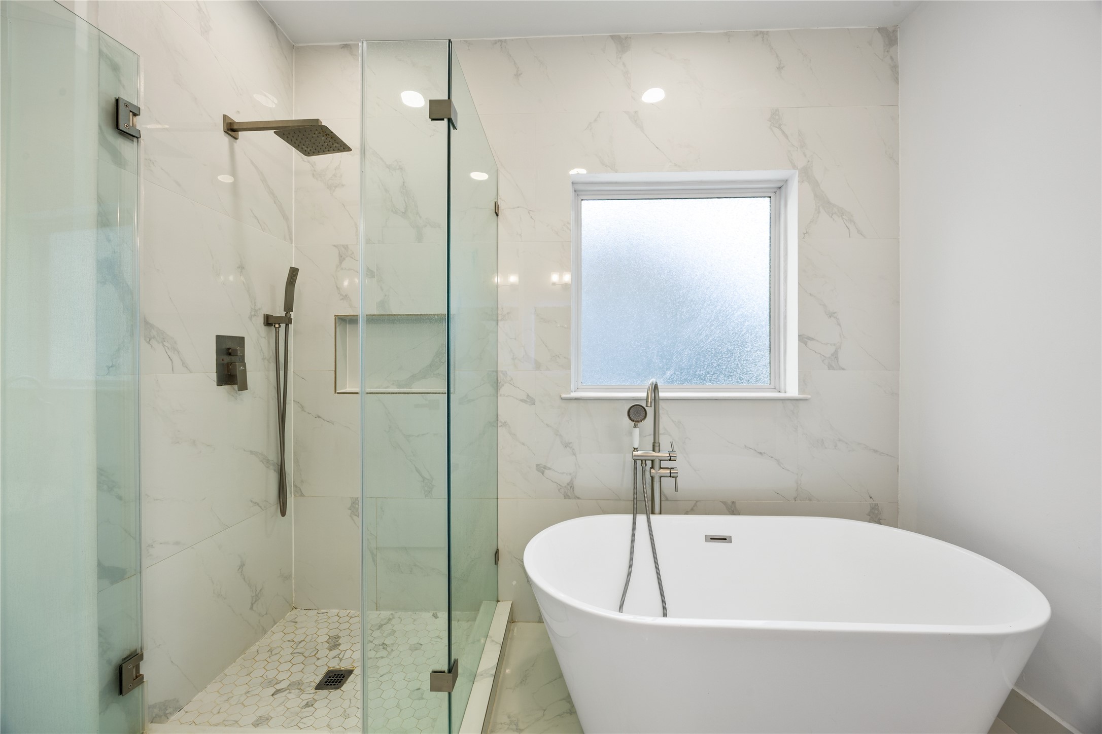 1121 Austin Street Rosenberg, TX 77471 - Photo 30 of 44 This modern bathroom features a sleek glass-enclosed shower with a rainfall showerhead and a freestanding bathtub. The walls and floors are adorned with elegant tiles, creating a luxurious and serene atmosphere.