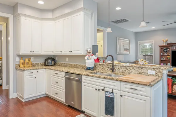 a kitchen with granite countertop a sink cabinets and wooden floor
