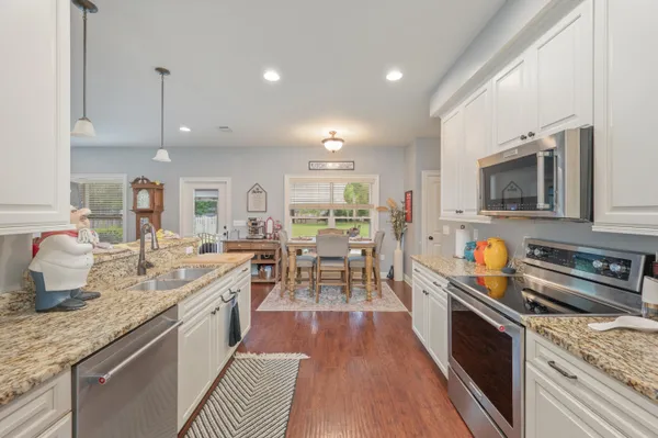 a large kitchen with stainless steel appliances granite countertop a lot of counter space and a wooden floor