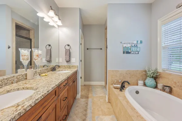 a bathroom with a granite countertop tub double vanity sink and a large mirror