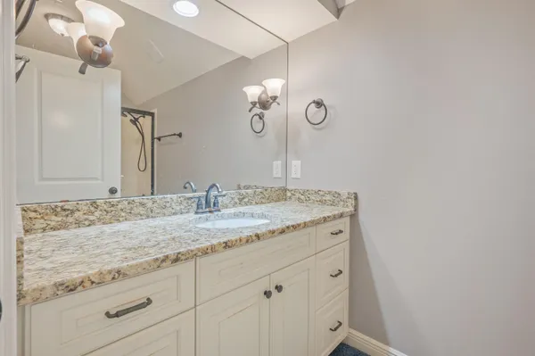 a bathroom with a granite countertop sink and a mirror