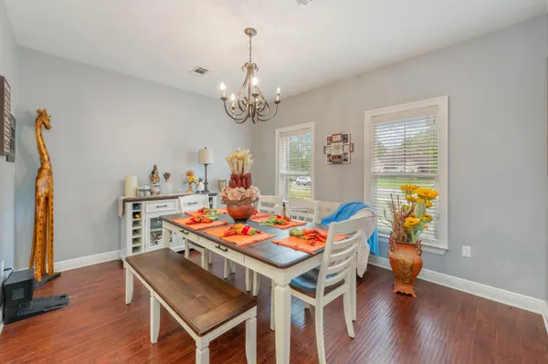 a dining room with furniture a chandelier and wooden floor