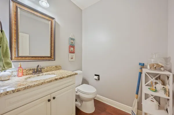 a bathroom with a granite countertop sink vanity mirror and toilet