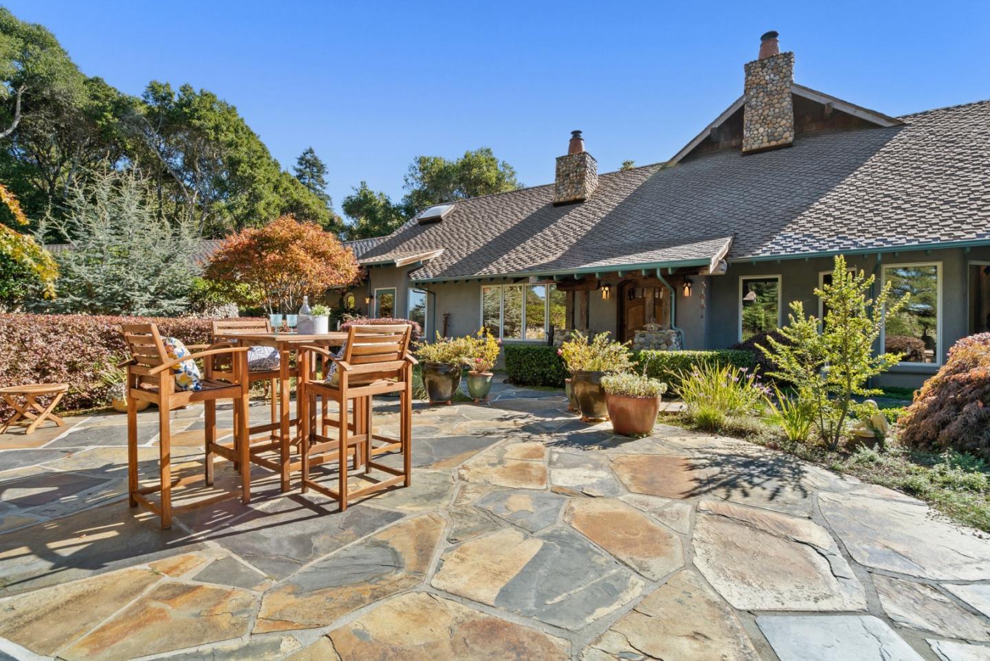 a view of a patio with table and chairs potted plants and large tree