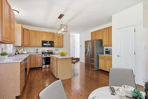 a kitchen with a refrigerator a stove top oven a sink dishwasher and wooden cabinets