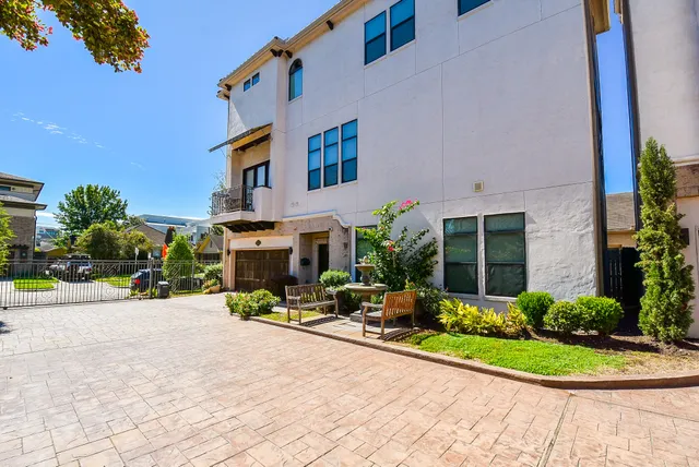 a view of a building with potted plants and a car park in front of it