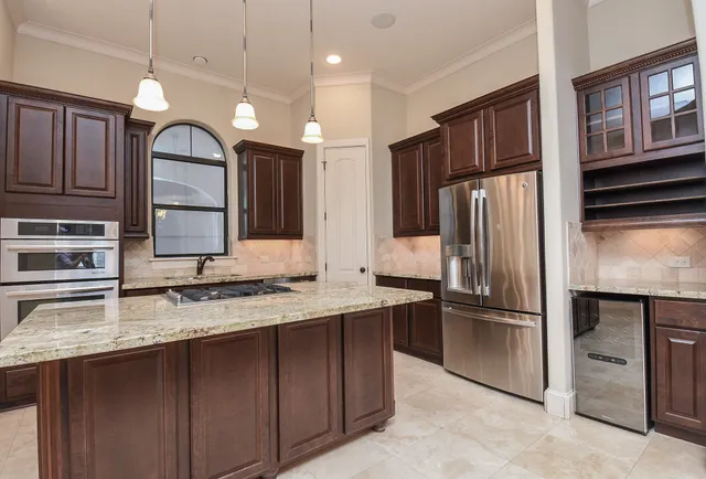 a kitchen with stainless steel appliances granite countertop a refrigerator a stove and a sink