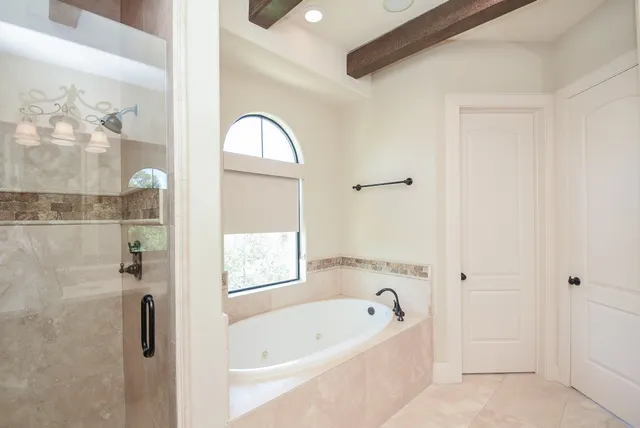 a bathroom with a bathtub a shower and a window