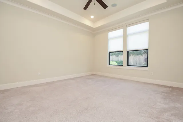 an empty room with chandelier fan and windows