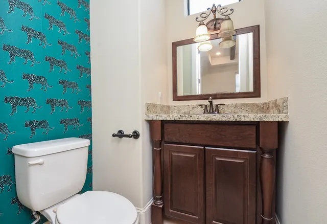 a bathroom with a granite countertop toilet sink and mirror