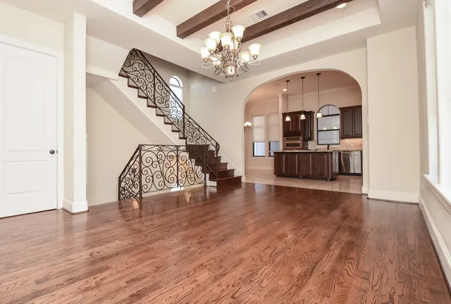 a view of a livingroom with wooden floor staircase and kitchen view