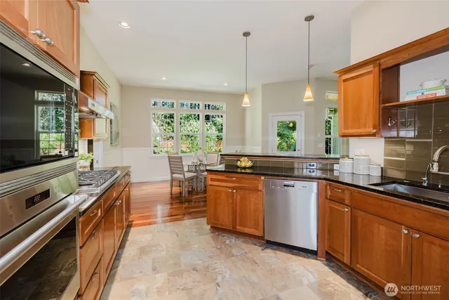 a kitchen with stainless steel appliances granite countertop a stove a sink and a wooden floors