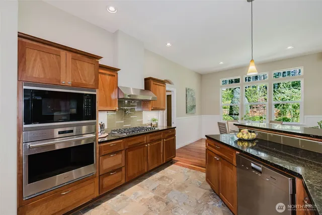 a kitchen with stainless steel appliances granite countertop a stove and a wooden cabinets