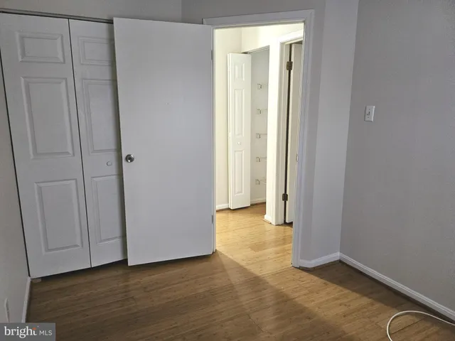 an empty room with wooden floor and closet area