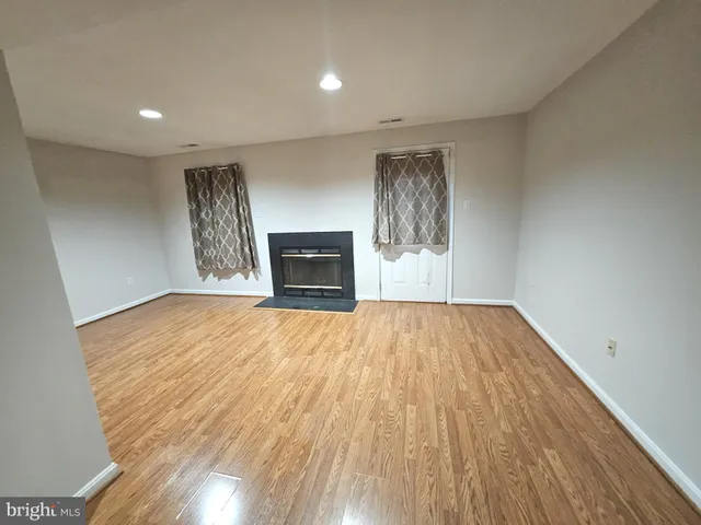 a view of empty room with wooden floor and fireplace