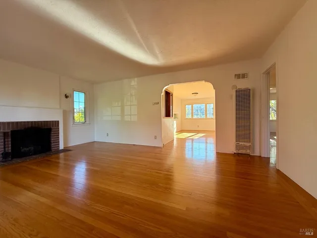 a view of empty room with wooden floor and fireplace