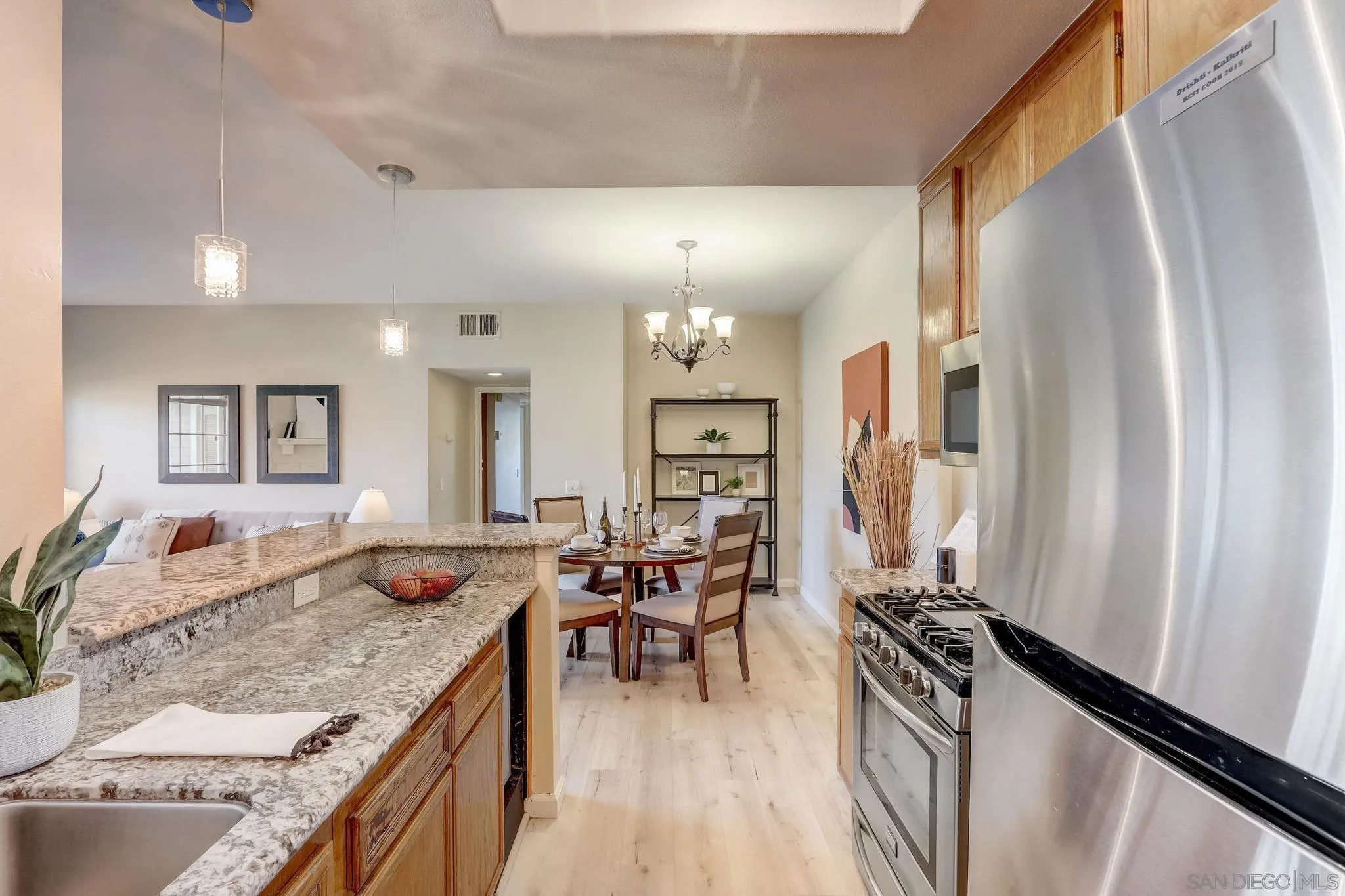 13832 Midland Road Poway, CA 92064 - Photo 14 of 36 a kitchen with stainless steel appliances granite countertop a refrigerator a stove a sink dishwasher and couches with wooden floor