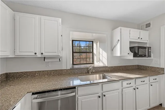 a kitchen with granite countertop white cabinets and sink