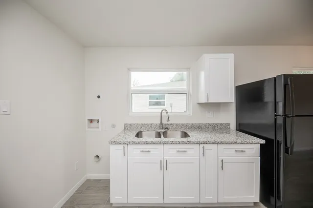 a kitchen with granite countertop white cabinets and refrigerator