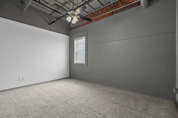 an empty room with a chandelier fan and windows
