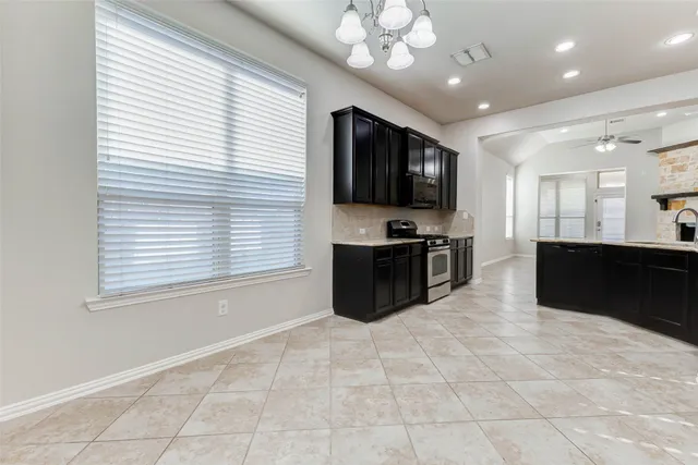 a view of kitchen with stainless steel appliances granite countertop cabinets and chandelier