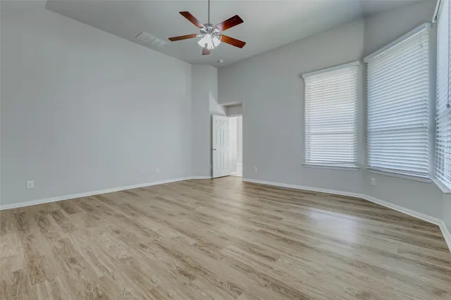 an empty room with wooden floor and windows