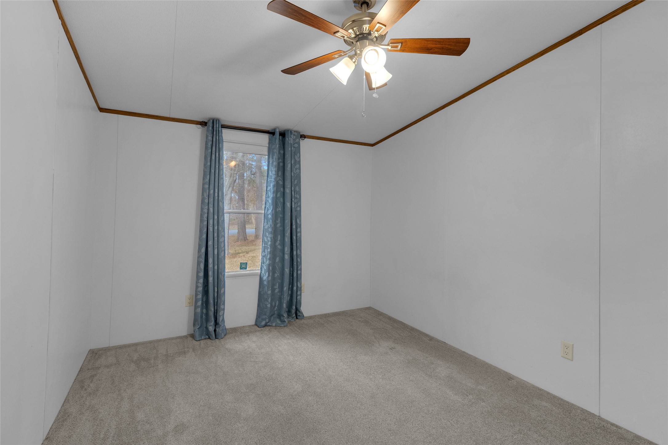 22094 Spear Road Porter, TX 77365 - Photo 32 of 45 Second Bedroom features neutral-colored walls and carpet, a ceiling fan with lights, and a window with blue curtains, providing a cozy and simple space.
