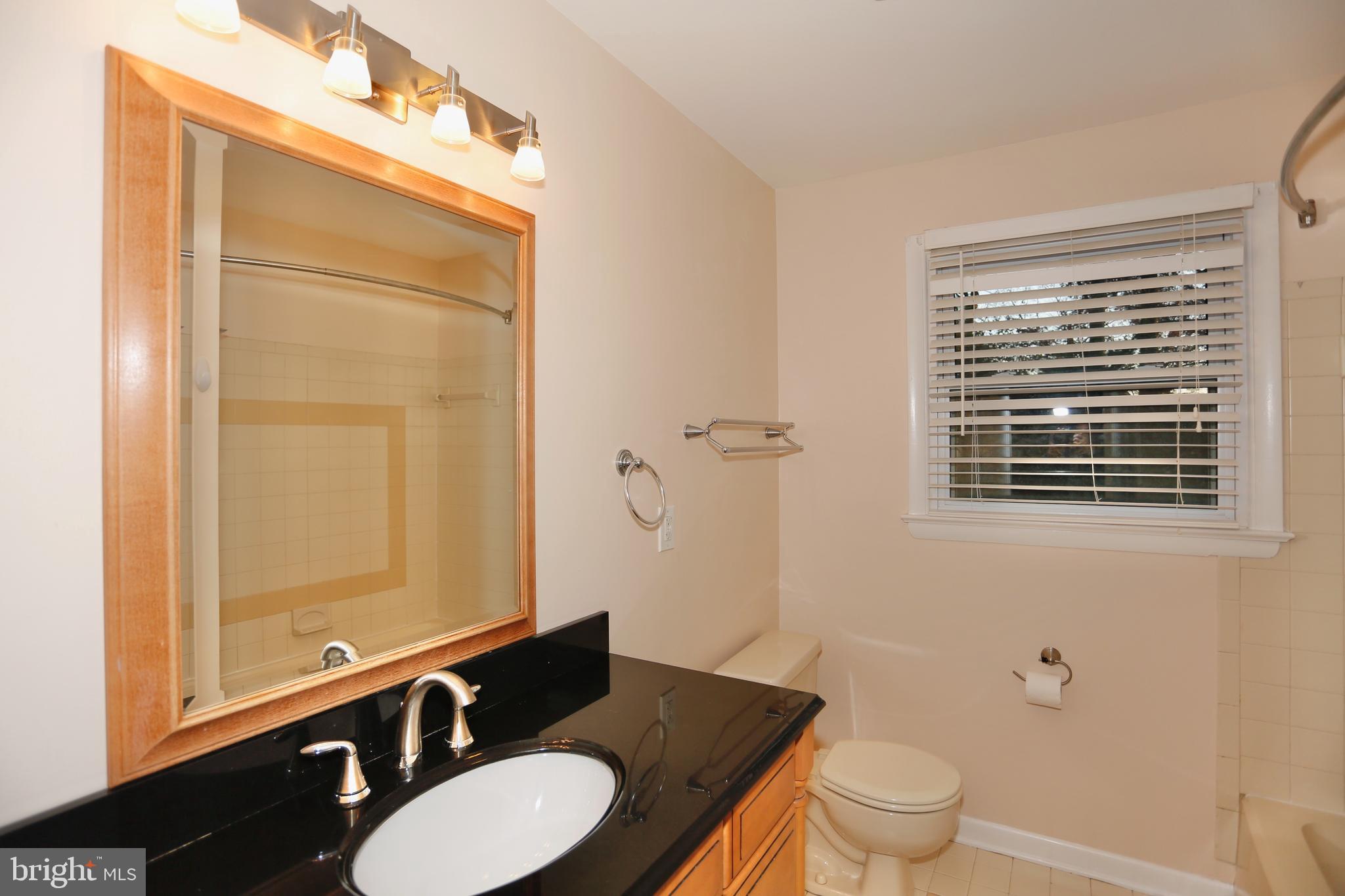 6308 Marywood Road Bethesda, MD 20817 - Photo 26 of 30 a bathroom with a granite countertop toilet a sink a mirror and a shower