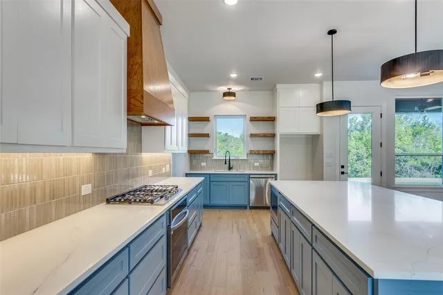 a kitchen with kitchen island granite countertop a sink a counter space appliances and cabinets