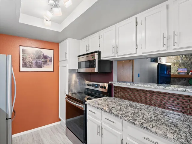 a kitchen with stainless steel appliances granite countertop a stove a sink and a microwave