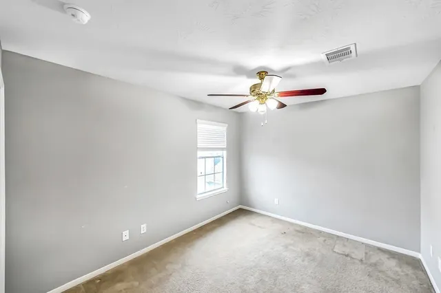 an empty room with windows and fan