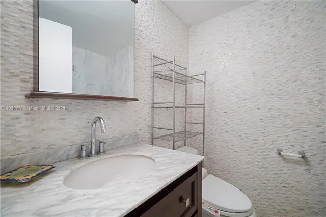 a bathroom with a granite countertop sink toilet and mirror