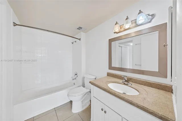 a bathroom with a granite countertop sink a toilet a mirror and shower